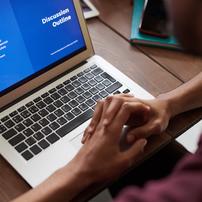 A laptop showing a blue PowerPoint slide saying "discussion outline"