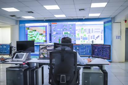 A man using a desktop computer with many monitors