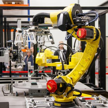 A yellow robotic arm in an assembly line