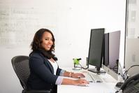 A businesswoman smiling at the camera at a computer