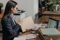 A businesswoman opening a manilla file in front of a laptop