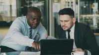 A man pointing out something on a laptop screen to another man to his side