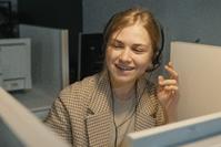 A businesswoman in a cubicle talking into a headset