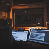 A person in a sound booth using two screens showing various levels