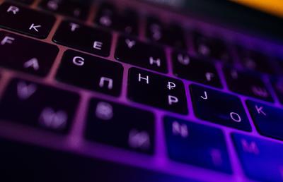 black computer keyboard with purple backlighting on the keys