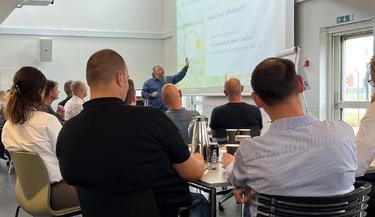 Deltagere sidder afslappede og smilende og arbejder sammen på et kursus.