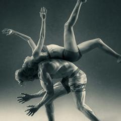 A woman flipping over a man, back to back