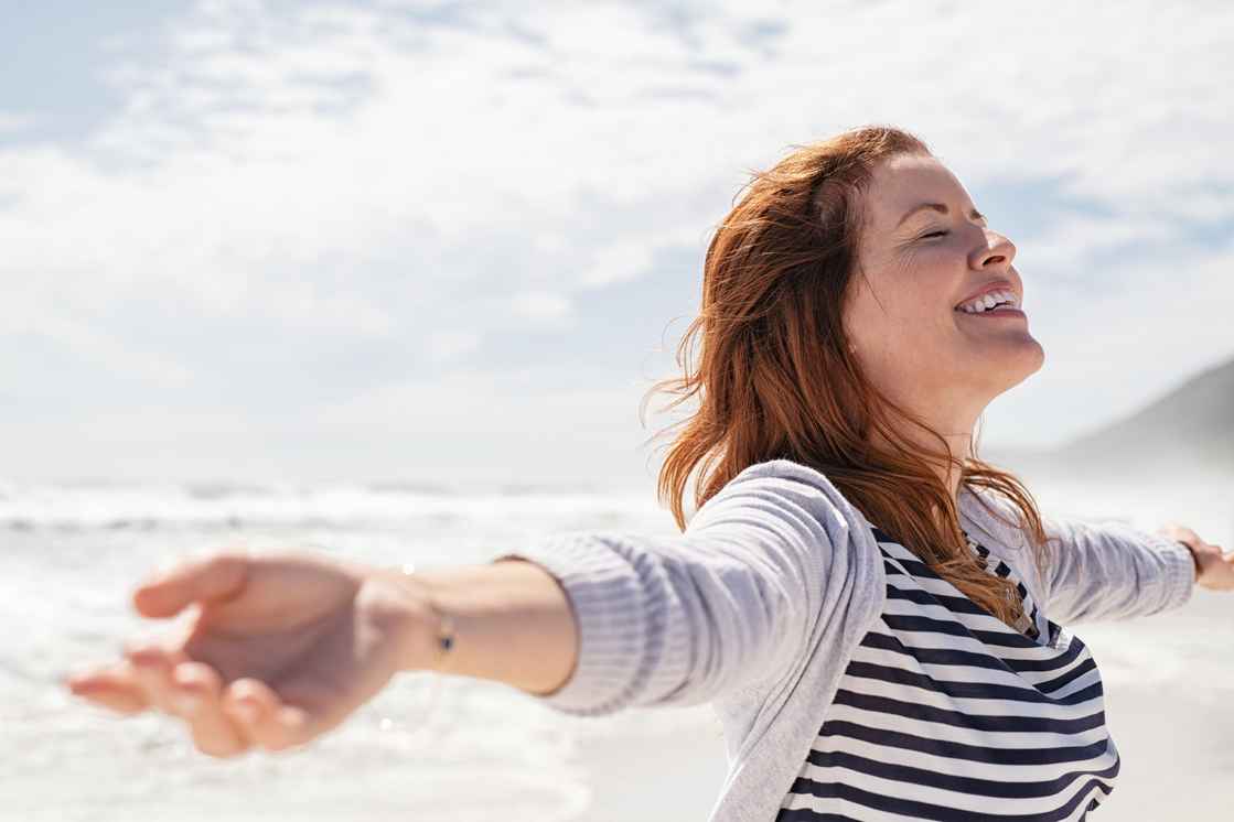 Naturlig kvinde glad ved stranden