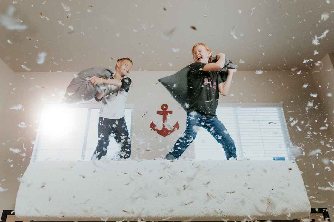 two boys on bed pillow fight