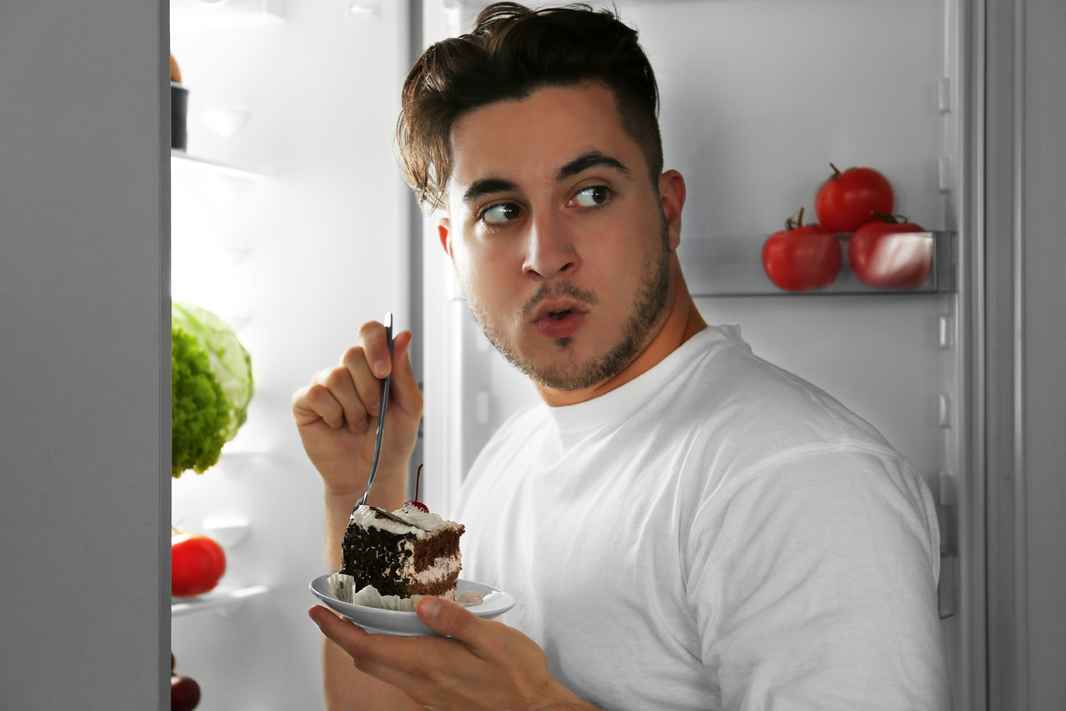 man eating cake at fridge