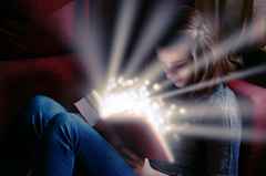 Girl reading book with sparkles emanating from the pages