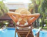 woman lying by sunny poolside relaxing crop