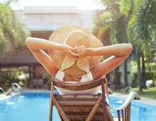 woman lying by sunny poolside relaxing crop