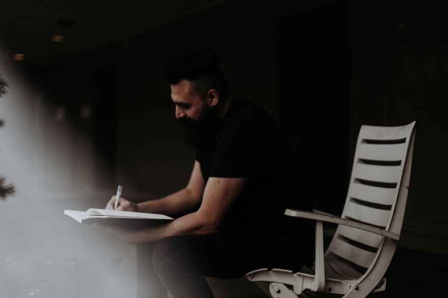 man on a chair writing notes