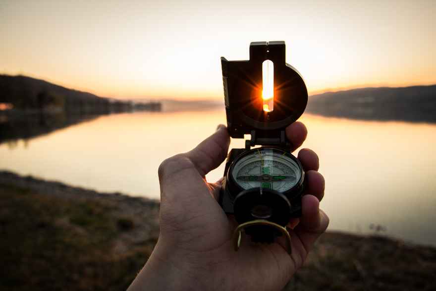 hand-holding-compass-at-sunset