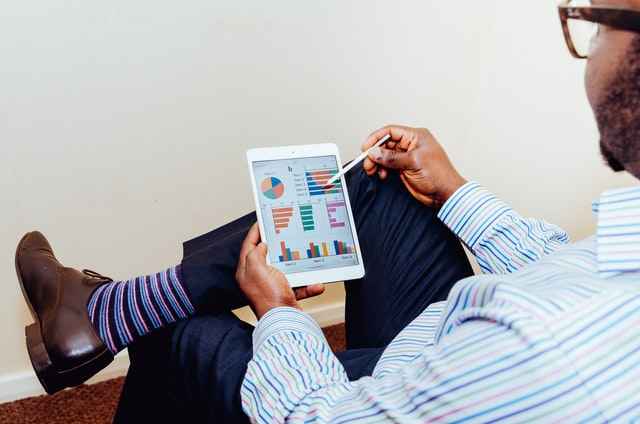 man sitting looking at charts on a tablet screen
