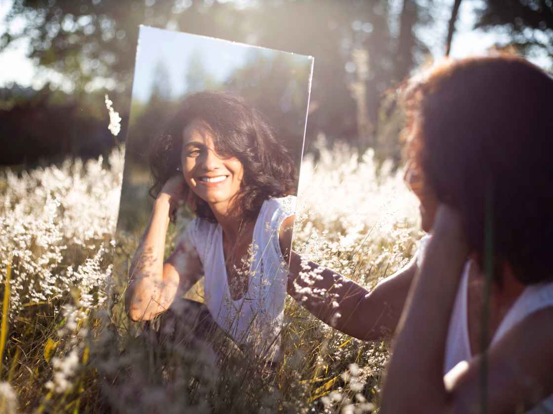 kvinde kigger kærligt i spejl i naturen