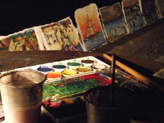 table-with-paints-brushes-and-small-paintings