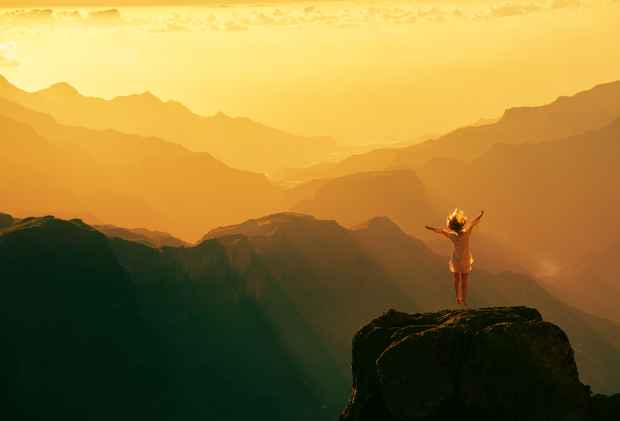 kvinde hopper på bjergtop i fabelagtigt landskab - frihed - fri for frygt