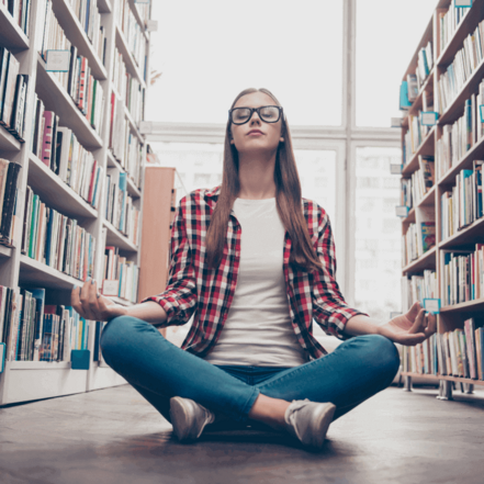 Kvinde der sidder og meditere i et bibliotek
