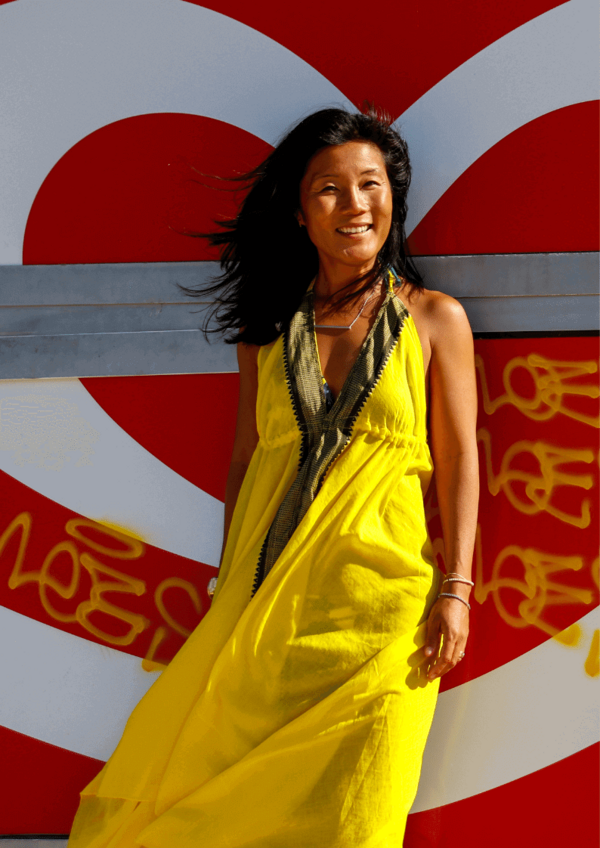 Smilende kvinde i gul kjole foran et hjerte i rødt og hvidt