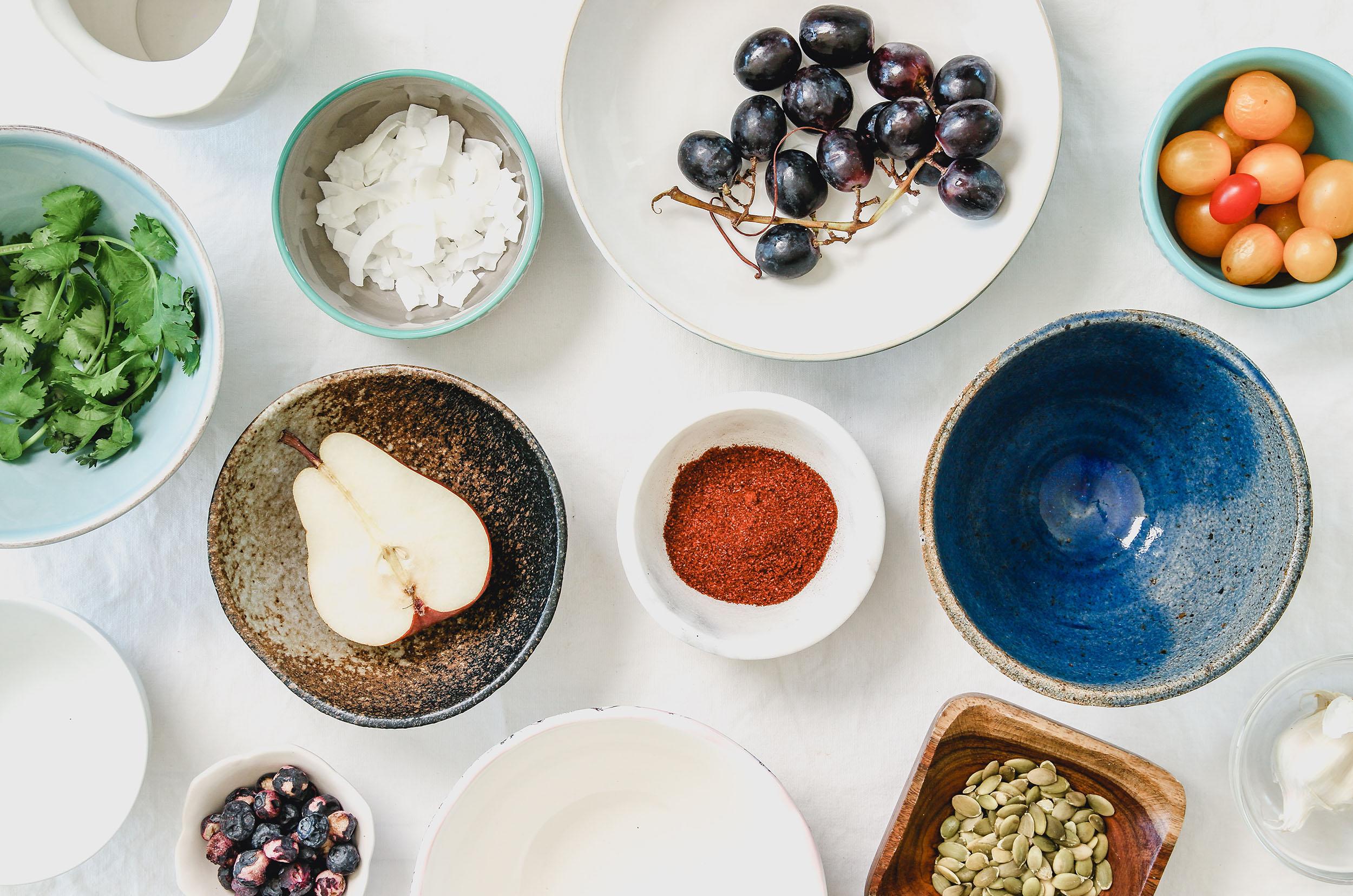 neutral-assortment-of-fruits-vegetable-and-herbs-in-bowls-on-a-white-table