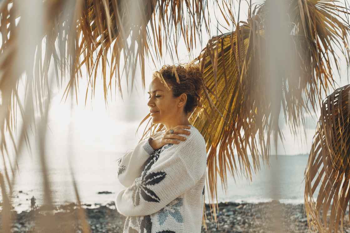 Simona Pilolla krammer sig selv ved palmer og stranden