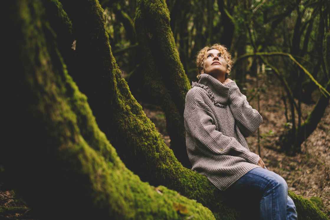 Simona Pilolla sidder ved træ i skoven og kigger op