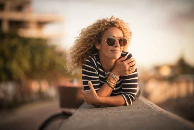 Simona Pilolla ligger på mur i solen med cykel i baggrunden og smiler