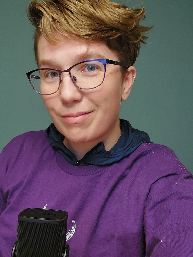Foto af en hvid person med brunt hår og lilla briller