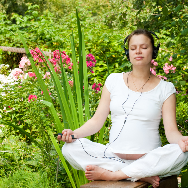 Mom meditating with headphones in garden