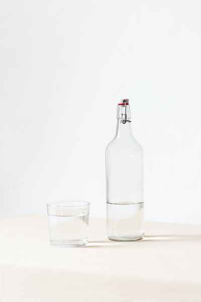 glass bottle with metal clasp stopper and half full glass