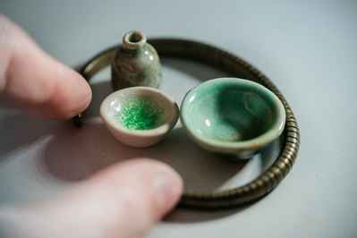 tiny bowls and bottles with fingers to show scale
